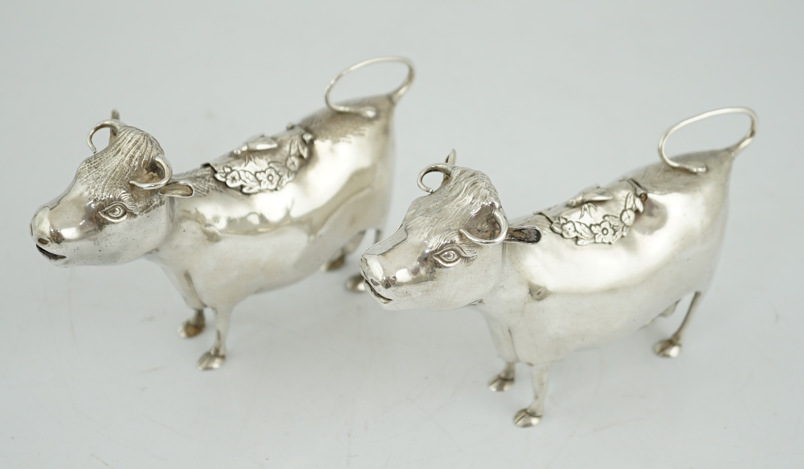 A pair of Elizabeth II silver cow creamers, by Heming & Co